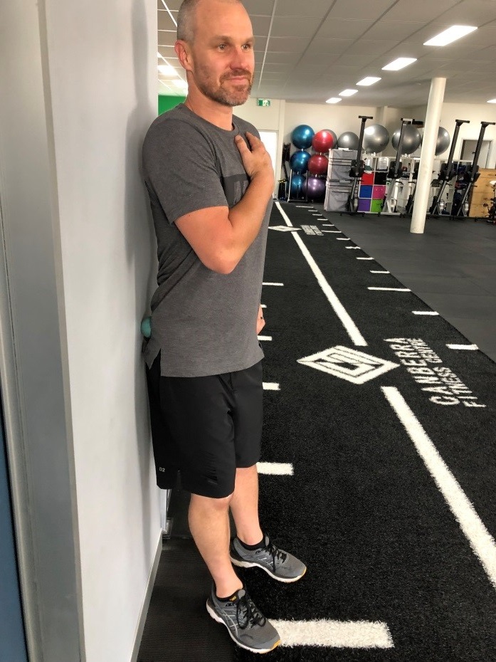 Antony Choice, Director and Soft Tissue Therapist at Myogen, demonstrating self-massage with a tennis ball against a wall. 